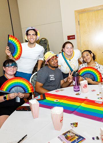 Five students with rainbow fans smiling at BSU's Big Queer Welcome event